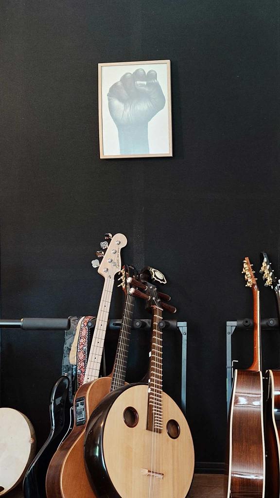 Guitars and drums are standing in front of a black wall.